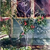 white wire arbor with red roses against a house