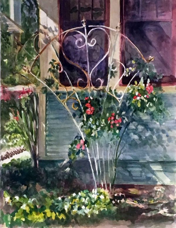 white wire arbor with red roses against a house